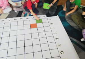 chłopiec układa na dużej macie do kodowania kolorowy kwadrat
