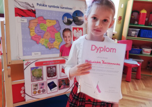 dziewczynka pokazuje dyplom za udział w konkursie "Nasze symbole narodowe"