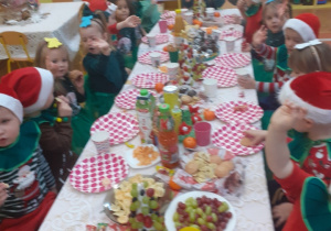 Zdjęcie przedstawia dzieci siedzące przy stole z przysmakami.