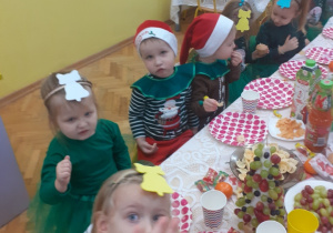 Zdjęcie przedstawia dzieci siedzące przy stole z przysmakami.