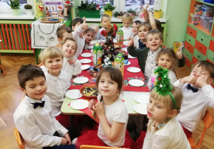 dzieci siedzą przy stole podczas uroczystego świątecznego podwieczorku.
