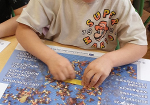 Na zdjęciu chłopiec szlifujący przy stoliku swój bursztynek.