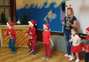 Na zdjęciu dzieci ubrane na czerwono z nauczycielką klaszczą w ręce.