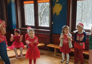 Na zdjęciu dzieci ubrane na czerwono klaszczą w ręce.