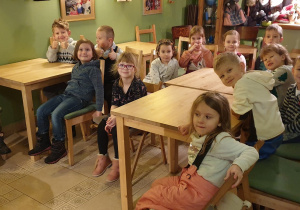 na zdjęciu dzieci siedzące przy stolikach.