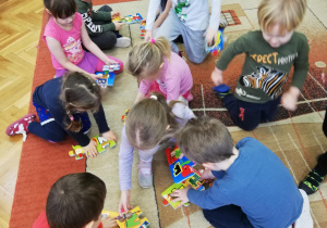 Dzieci na dywanie układają puzzle piankowe