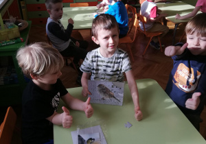 Dzieci przy stolikach w małych zespołach układają puzzle na czas​