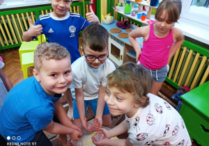 Na zdjęciu dzieci dotykają kostki lodu.