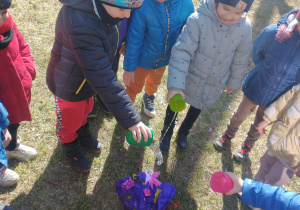 Dzieci polewają kukłę wodą z kubków