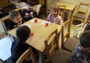 Dzieci przy kawiarnianym stoliku z baśniowym soczkiem