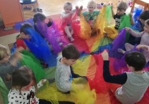 dzieci podczas zabaw muzyczno-ruchowych z wykorzystaniem kolorowych apaszek i chusty animacyjnej