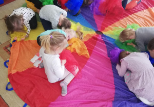 dzieci podczas zabaw muzyczno-ruchowych z wykorzystaniem kolorowych apaszek i chusty animacyjnej