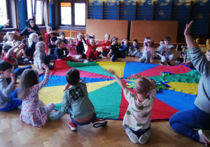 dzieci podczas zabawy z chustą animacyjną na sali gimnastycznej