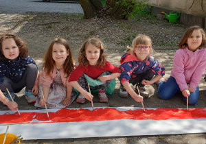 Na zdjęciu grupa dziewczynek malujących flagę.
