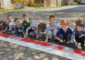 Na zdjęciu grupa chłopców malujących flagę Polski.