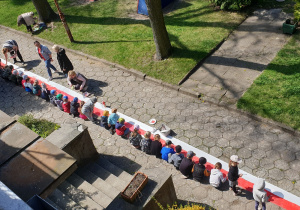 Na zdjęciu pokazane z góry dzieci malujące flagę o długości czterdziestu metrów.