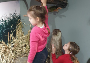 Na zdjęciu dwie dziewczynki przyglądają się figurom zwierząt.