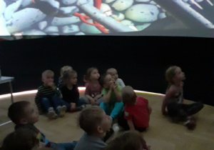 Na zdjęciu dzieci oglądają bajkę wyświetlaną na ścianach balonu sferycznego.