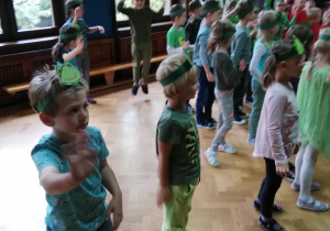Na zdjęciu dzieci z papierowymi opaskami emblematem Żabek na głowach wesoło tańczące