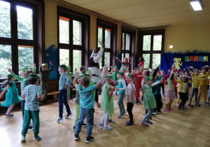 Na zdjęciu dzieci z papierowymi opaskami emblematem Żabek na głowach wesoło tańczące