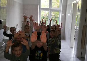 Dzieci w łazience przedszkolnej pokazują umyte ręce