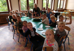Dzieci na jadalni przy wspólnym stole czekają na degustację sałatki
