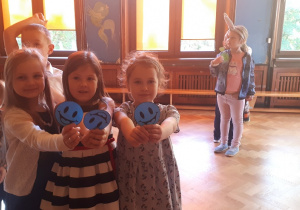 na zdjęciu trzy dziewczynki pokazują niebieskie emblematy uśmiechniętej buzi