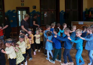 dzieci ubrane w niebieskie koszulki tańczą w wężyku