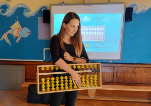 instruktorka zajęć z arytmetyki mentalnej prezentuje dzieciom liczydło Soroban