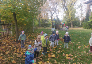 dzieci podczas zbierania kolorowych jesiennych liści w ogrodzie przedszkolnym