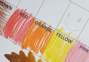 Na zdjęciu fragment karty pracy z kolorami i pomarańczowo-żółty liść
