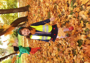 Na zdjęciu dziewczynka podrzuca jesienne, kolorowe liście.