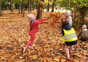Na zdjęciu wesołe dzieci rzucające w siebie jesiennymi, kolorowymi liśćmi.