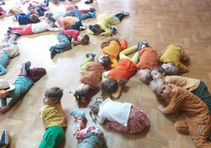 Dzieci w jesiennych kostiumach leżą na podłodze – zabawa „Magiczna liczba siedem”