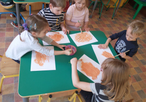 Dzieci malują dynie na kartkach