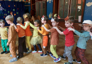 Dzieci w jesiennych kostiumach tańczą w wężyku