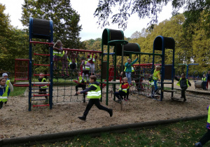Na zdjęciu dzieci bawią się na różnych przyrządach na parkowym placu zabaw