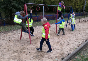 Na zdjęciu dzieci bawią się na różnych przyrządach na parkowym placu zabaw