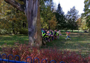 Na zdjęciu dzieci stoją przy jednym z najstarszych drzew w parku " 3-go maja"