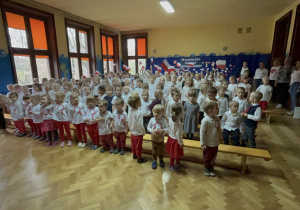 Dzieci podczas wspólnego wykonywania hymnu Polski na sali gimnastycznej przedszkola.