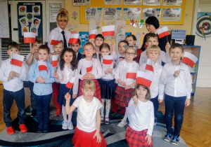Grupa 6 wraz z nauczycielkami w biało czerwonych strojach z flagami Polski