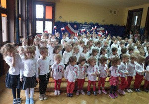 Dzieci wspólnie śpiewają hymn na sali gimnastycznej.
