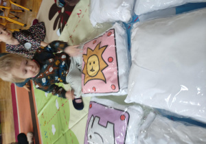 dziewczynka podczas gry memory kolorowymi poduszkami
