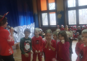 Dzieci przedszkolne słuchają zasad przedstawianych przez nauczyciela na temat konkursu Mikołajkowego.
