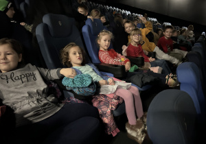 Dzieci siedzą na sali kinowej i oczekują na rozpoczęcie filmu.
