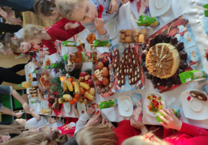 Dzieci siedzący przy stole zastawionym smakołykami