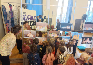 Dzieci oglądają zdjęcia przedstawiające spektakl „Kopciuszek”.