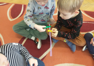 Dzieci podają sobie druciki za pomocą spinaczy