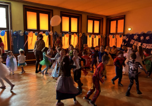Na zdjęciu grupa dzieci w karnawałowych przebraniach podczas zabawy na udekorowanej balonami sali