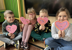 Na zdjęciu 4 dzieci trzyma własnoręcznie robione walentynki w kształcie serduszek